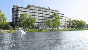 Un hotel de varios pisos con balcones, ubicado junto a un río tranquilo.