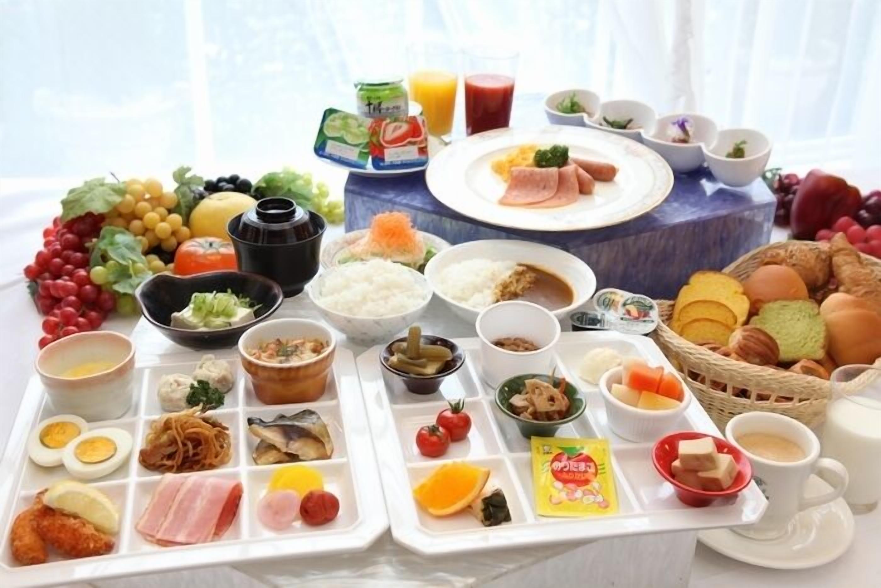 A breakfast buffet with various dishes, including fruits, vegetables, rice, and meats.