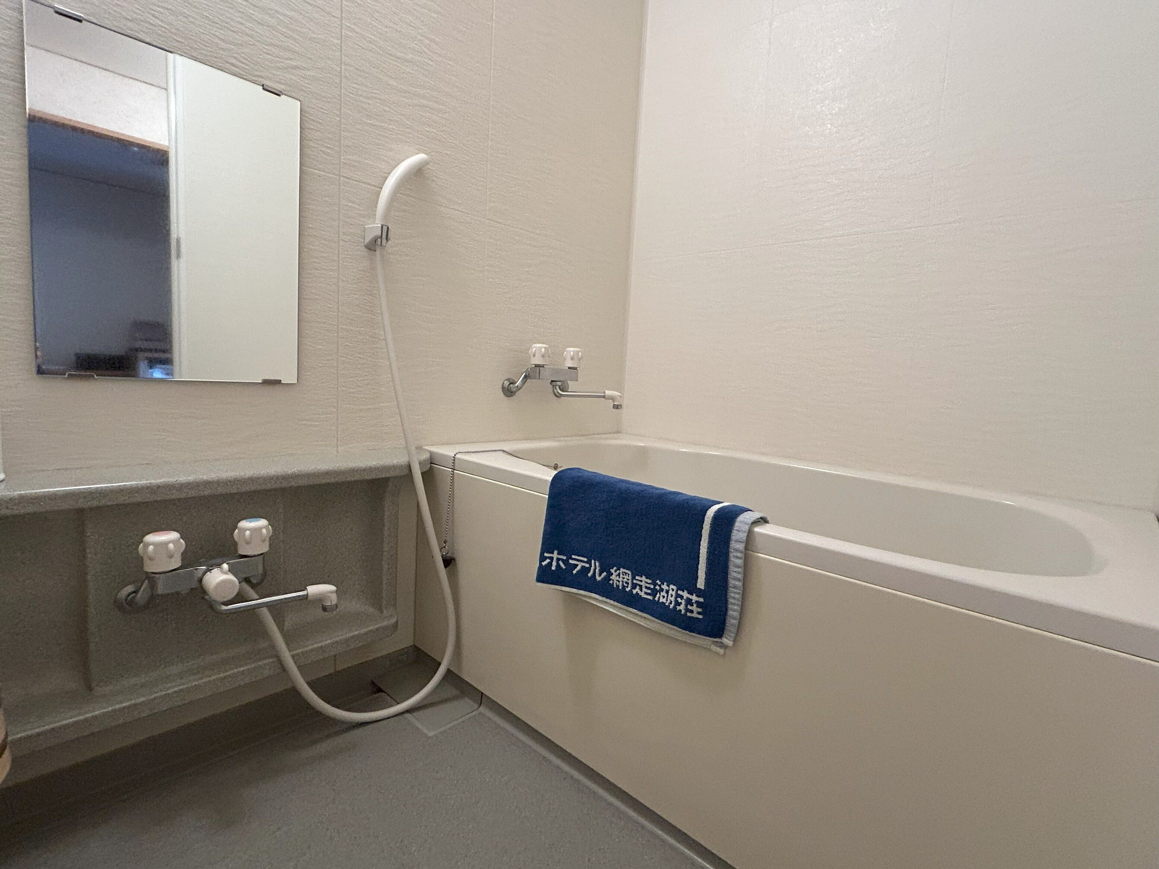 Un baño con bañera, una toalla colgando y un cabezal de ducha.