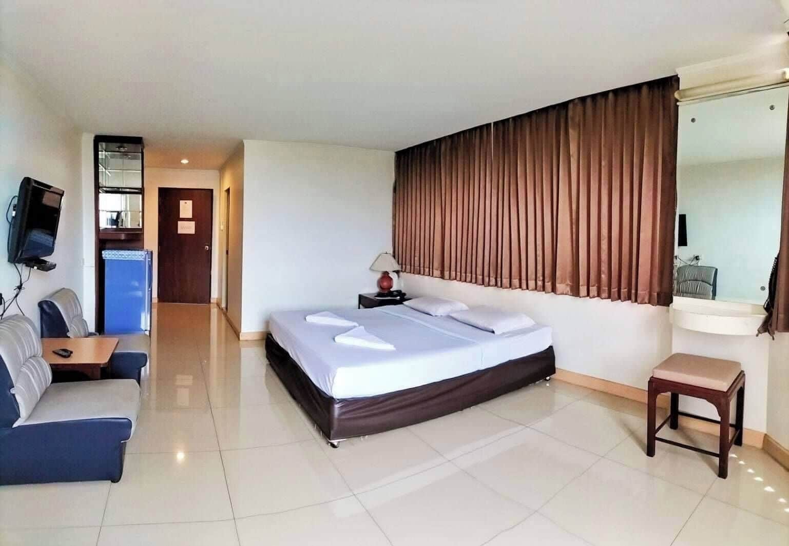 Ein Hotelzimmer mit Bett, Schreibtisch, Stuhl, Fernseher und Spiegel im Badezimmer.