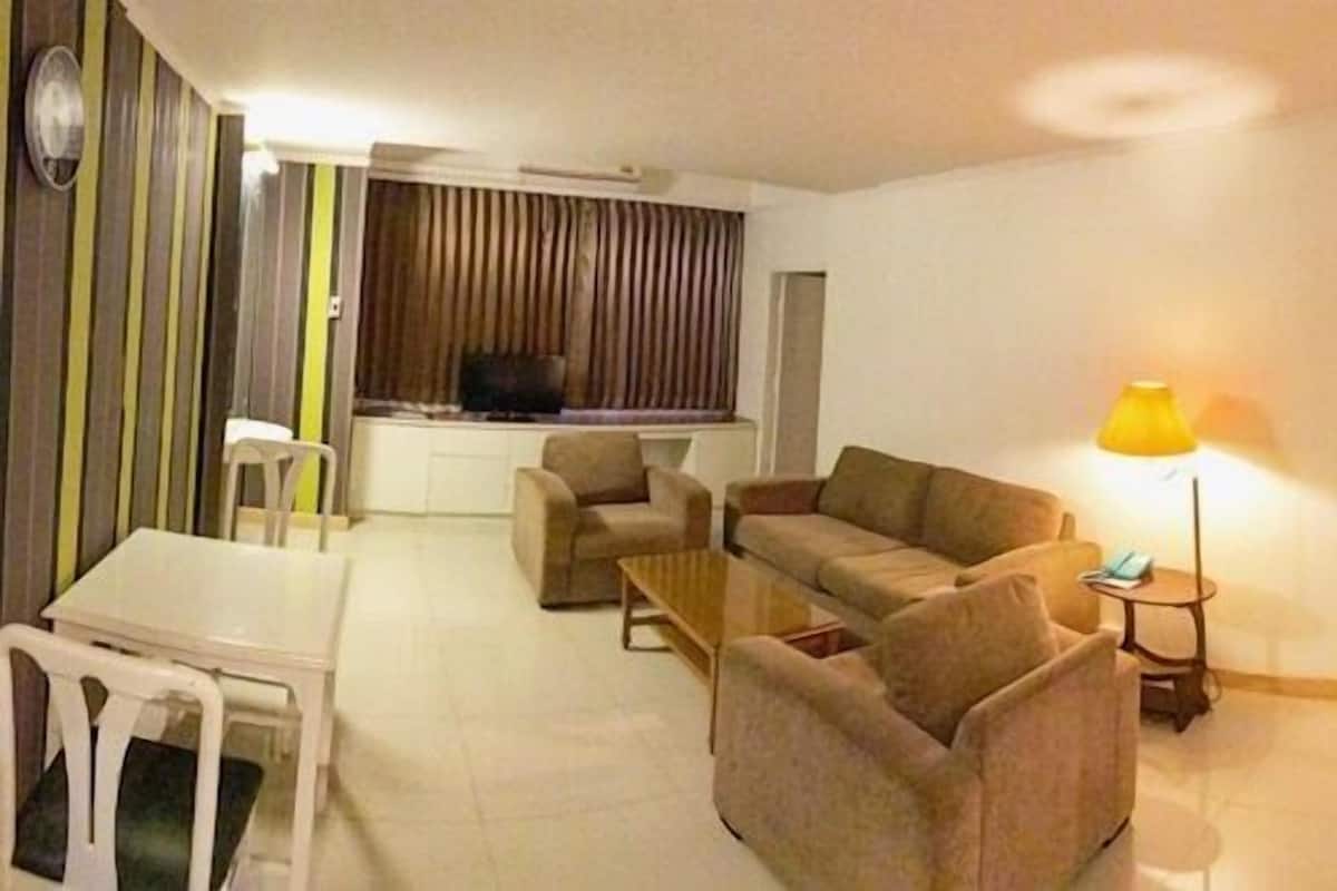 Ein Wohnzimmer mit einer Sofagarnitur, einem Couchtisch, einem Fernseher und einer Lampe.