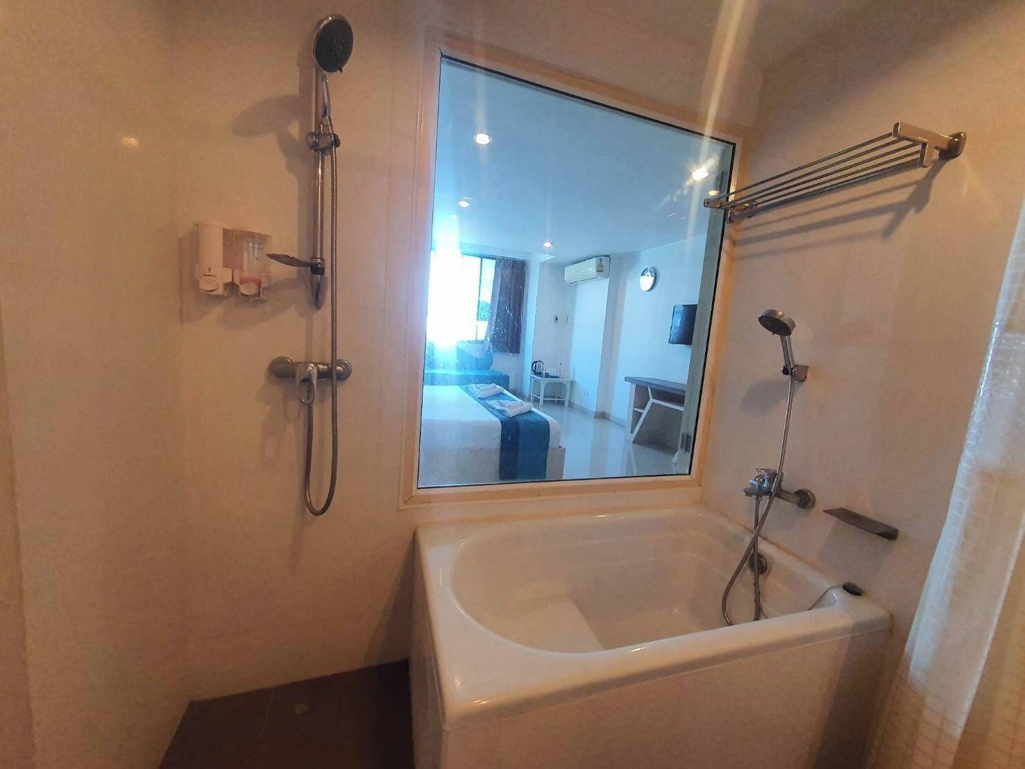 A modern bathroom with a large bathtub, a showerhead, and a mirror.