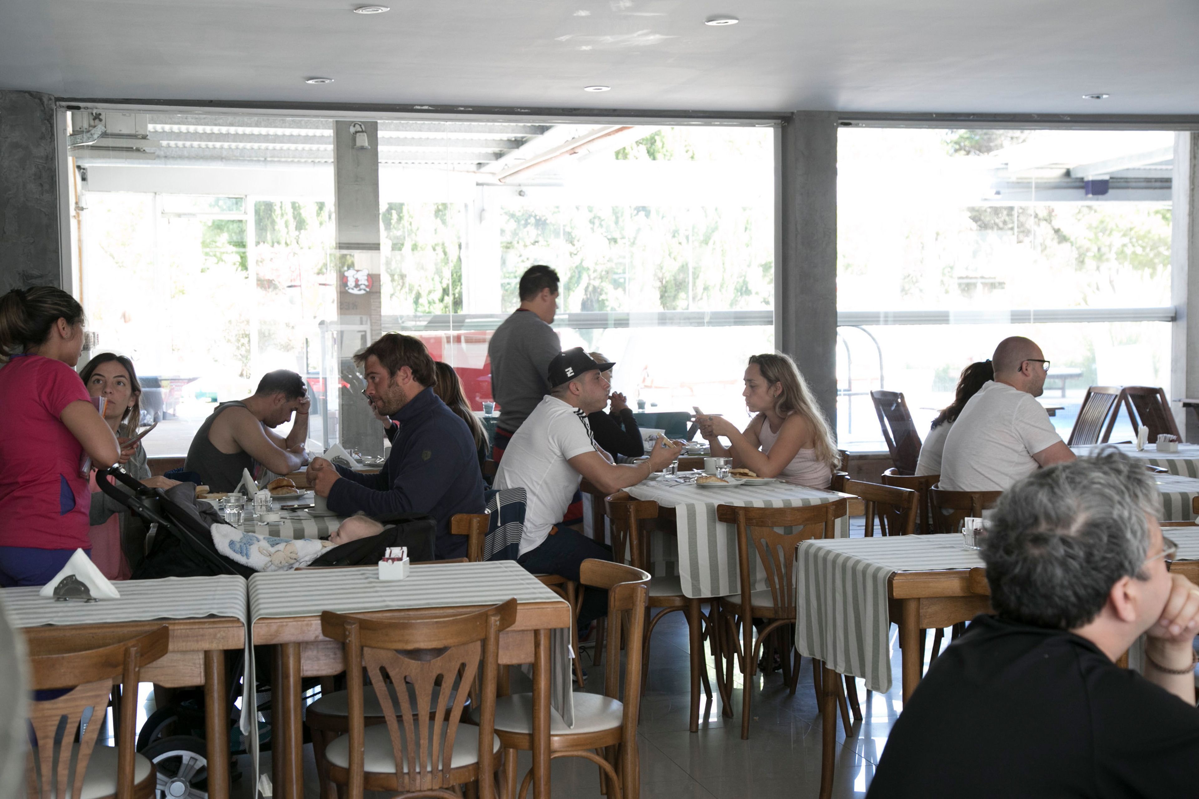 A restaurant with multiple tables and chairs, large windows, and a view of the outside.