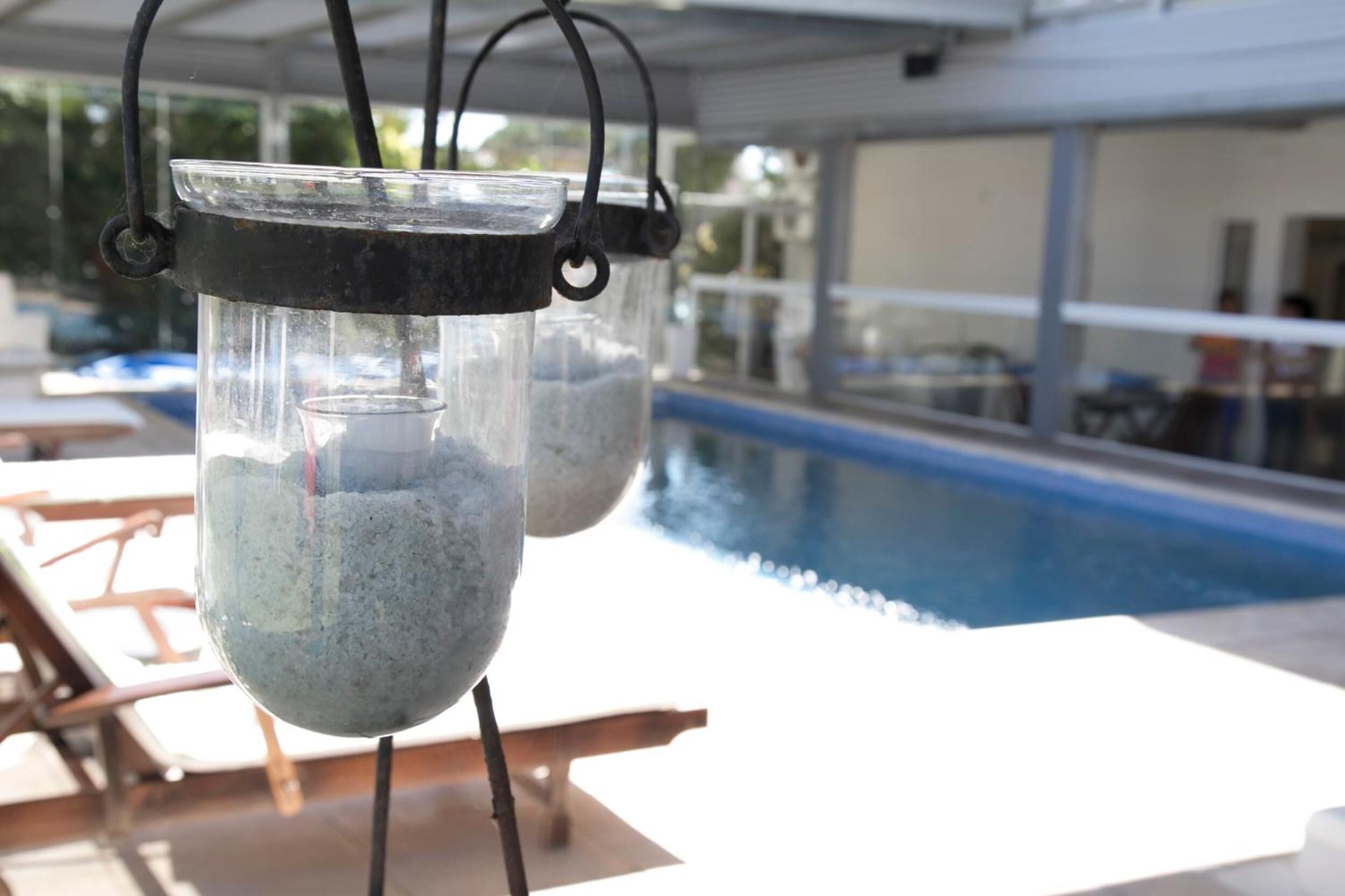 Área à beira da piscina com espreguiçadeiras e um candeeiro de vidro.