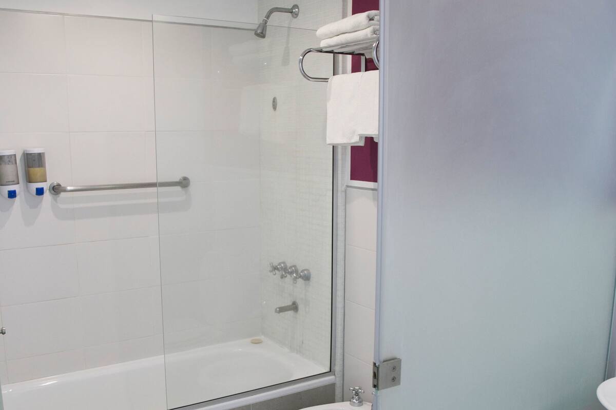 A modern bathroom with a glass-enclosed shower, a white toilet, and a sink.
