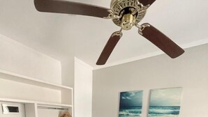 A bedroom with a bed, a ceiling fan, a wardrobe, a desk with a computer, and two wall-mounted paintings. - Hotel Valeria (Valeria del Mar)
