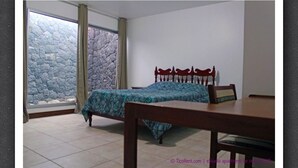 Un dormitorio con cama, mesita de noche de madera, una silla y pared de piedra.