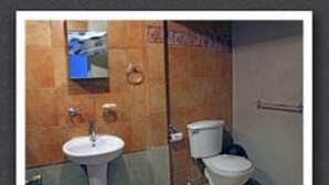 Un baño con lavamanos, inodoro y espejo.