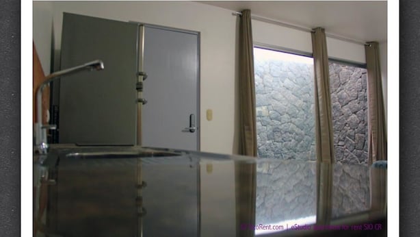 Una habitación con un armario metálico grande, una puerta y una ventana con cortinas.