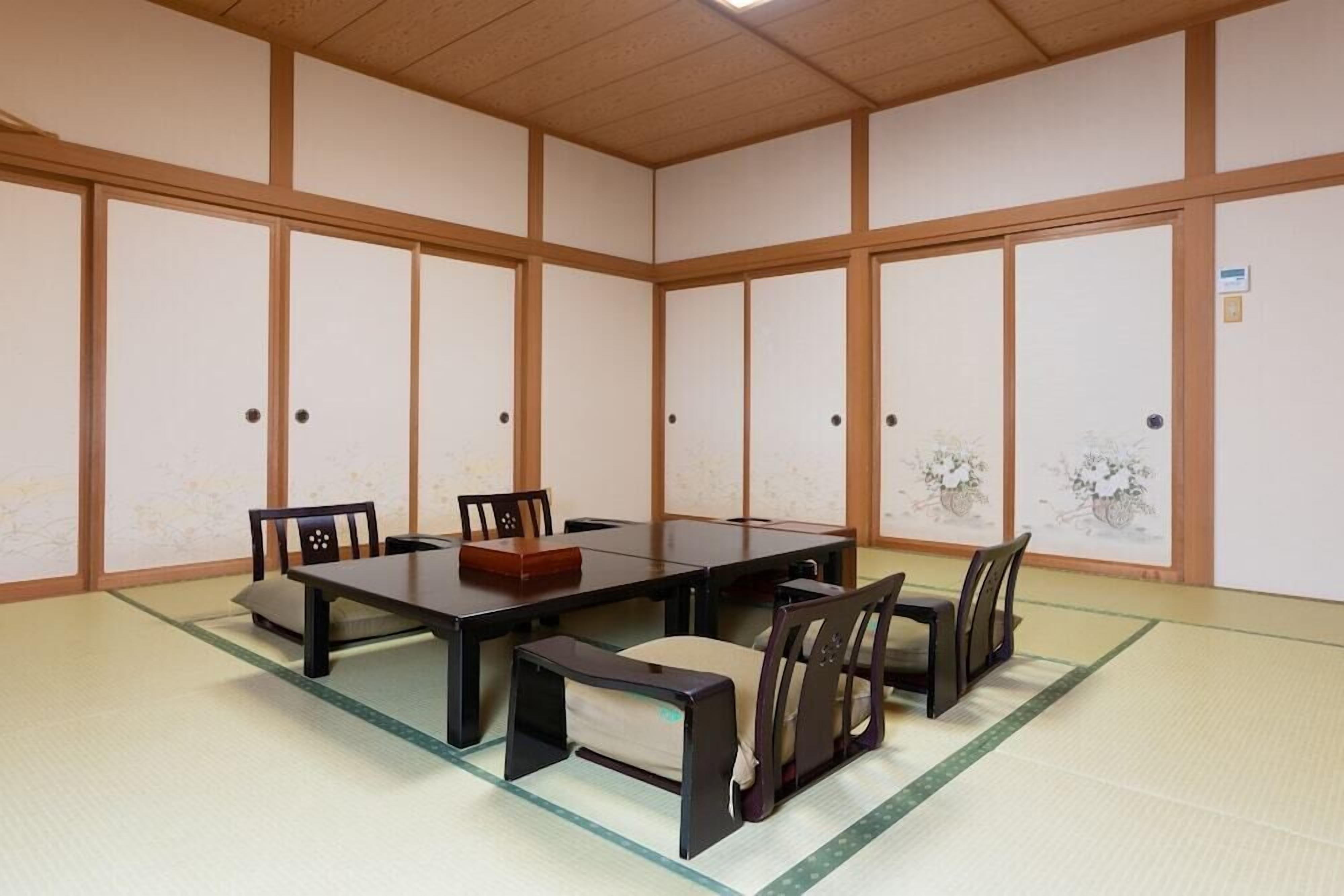 Um quarto japonês tradicional com tatames, uma mesa baixa e portas deslizantes de madeira.