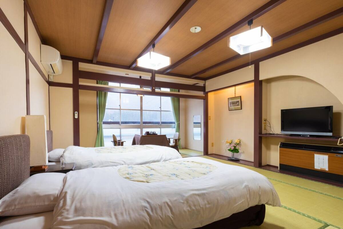 Ett hotellrum med två sängar, en tv, ett skrivbord och utsikt över havet.