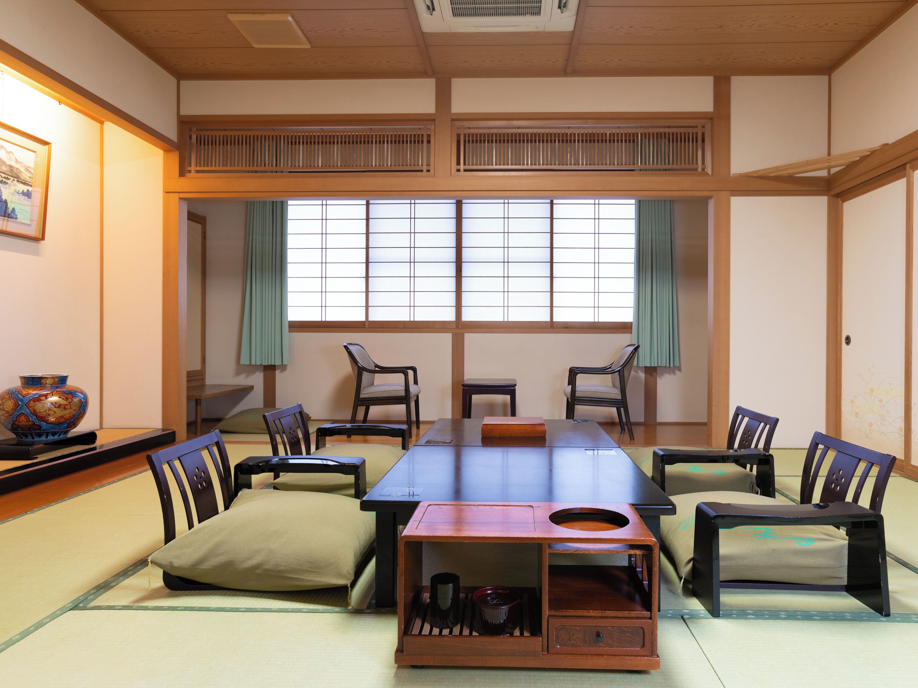 Um quarto japonês tradicional com tatames, uma mesa baixa e cadeiras.