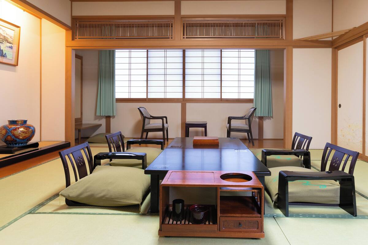 Ett traditionellt japanskt rum med tatamimattor på golvet, ett lågt bord och stolar.