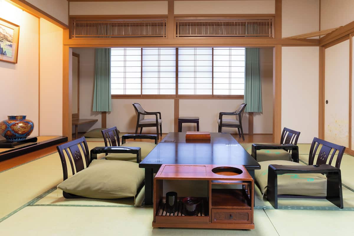 A traditional Japanese room with tatami flooring, a low table, and chairs.