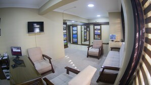 Un hall con mostrador de recepción, computadora, televisor de pantalla plana y zonas de estar.