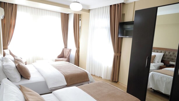 Una habitación de hotel con dos camas, una silla, un televisor y un armario.