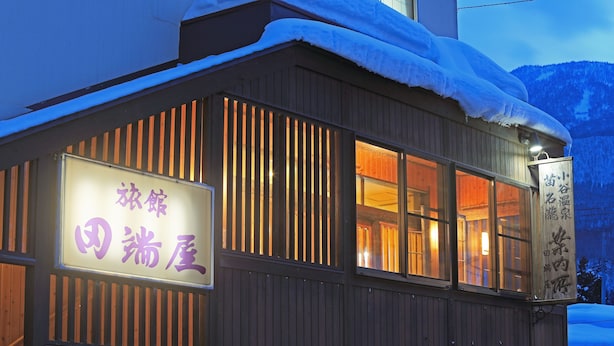 A building with a sign in Japanese, wooden exterior, and snow on the roof. - Iyashinoyado Ryokan Tabataya (Myoko)