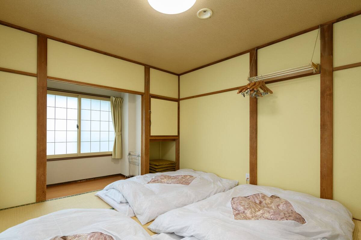 A traditional Japanese-style room with tatami flooring, a sliding door, and a ceiling fan.