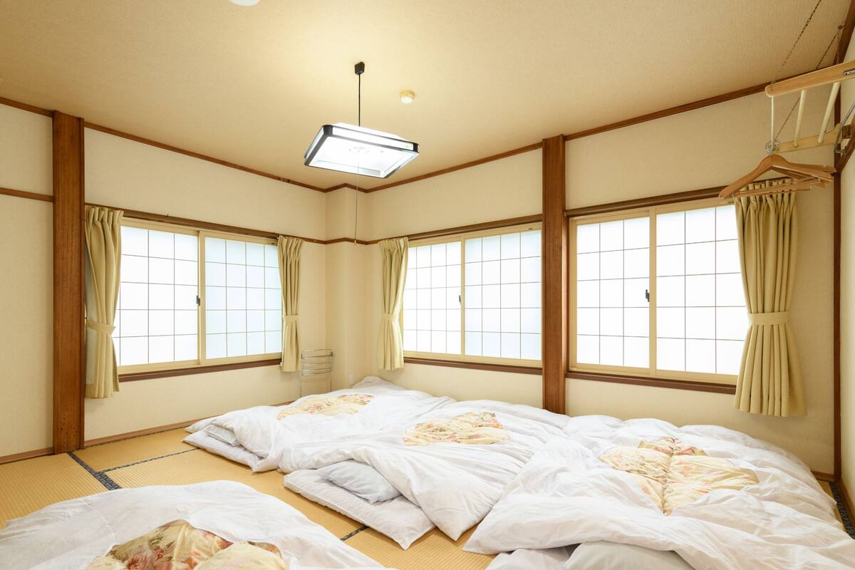A traditional Japanese room with tatami flooring, shoji screens, and a hanging wardrobe.