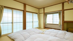 A traditional Japanese-style room with tatami flooring, shoji screens, and a futon bed. - Iyashinoyado Ryokan Tabataya (Myoko)