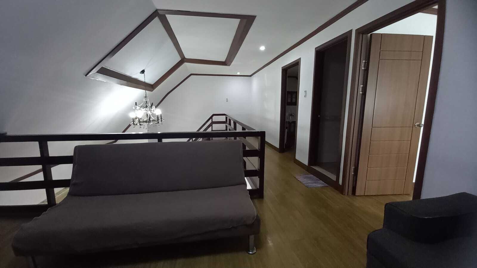 Uma sala de estar moderna com sofá, lustre e piso de madeira.