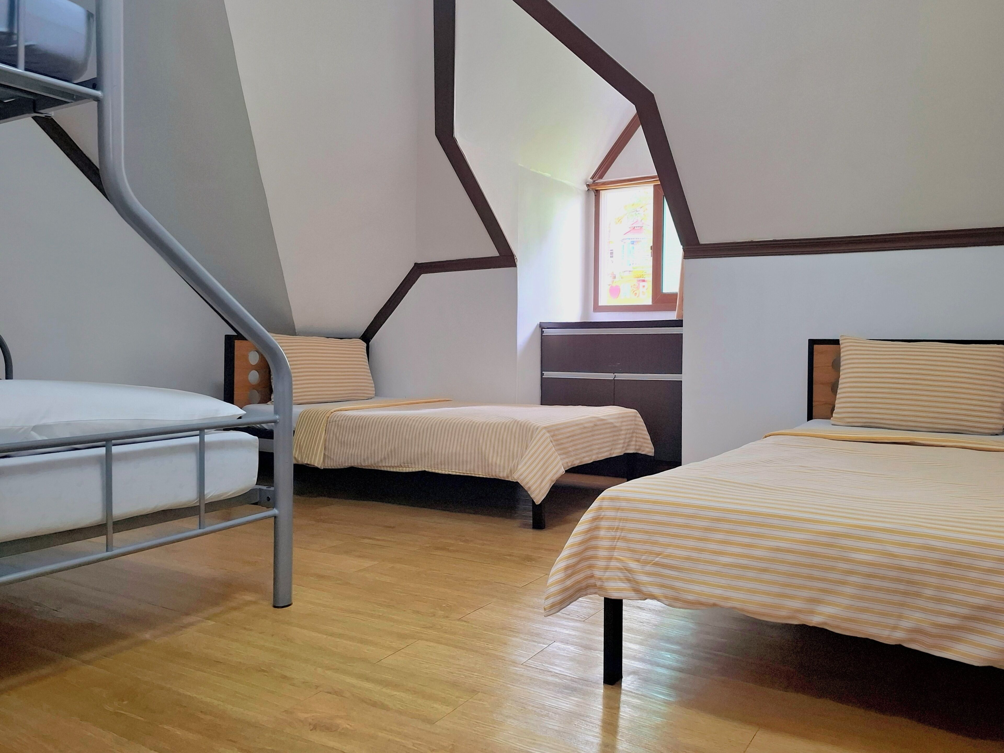 A dormitory room with bunk beds, a desk, and a window.