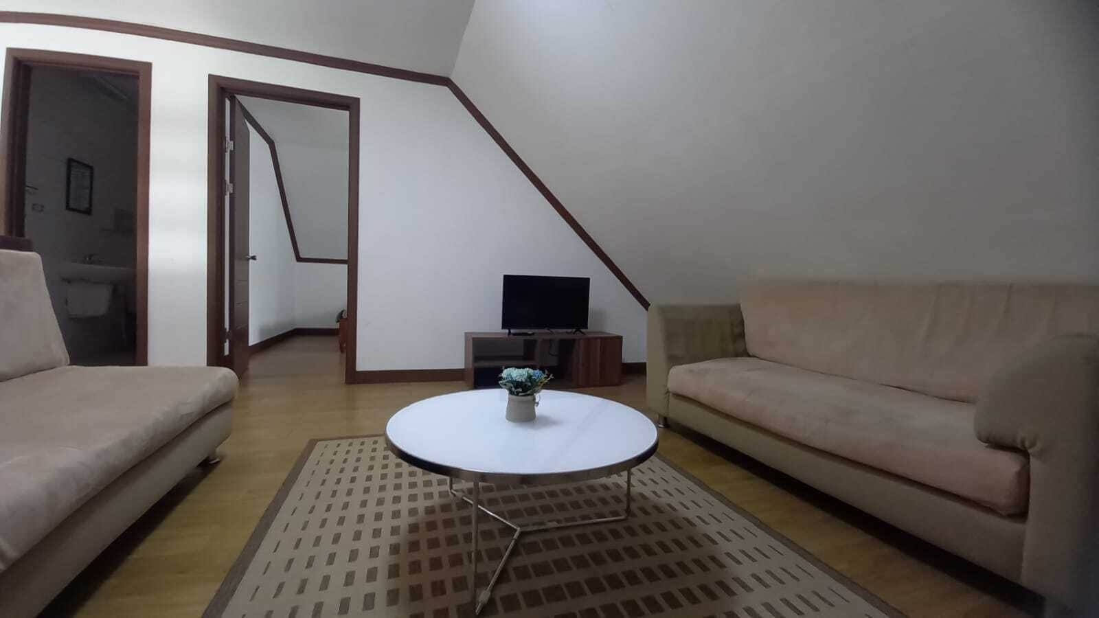 A living room with two sofas, a coffee table, a TV, and a staircase.