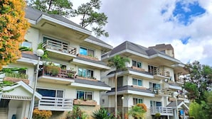 A multi-story hotel with balconies, outdoor seating, and a landscaped garden. - Prestige Vacation Apartments - Hanbi Mansions (Baguio)