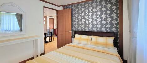 Un dormitorio con cama, ventana, puerta y vista a un comedor.