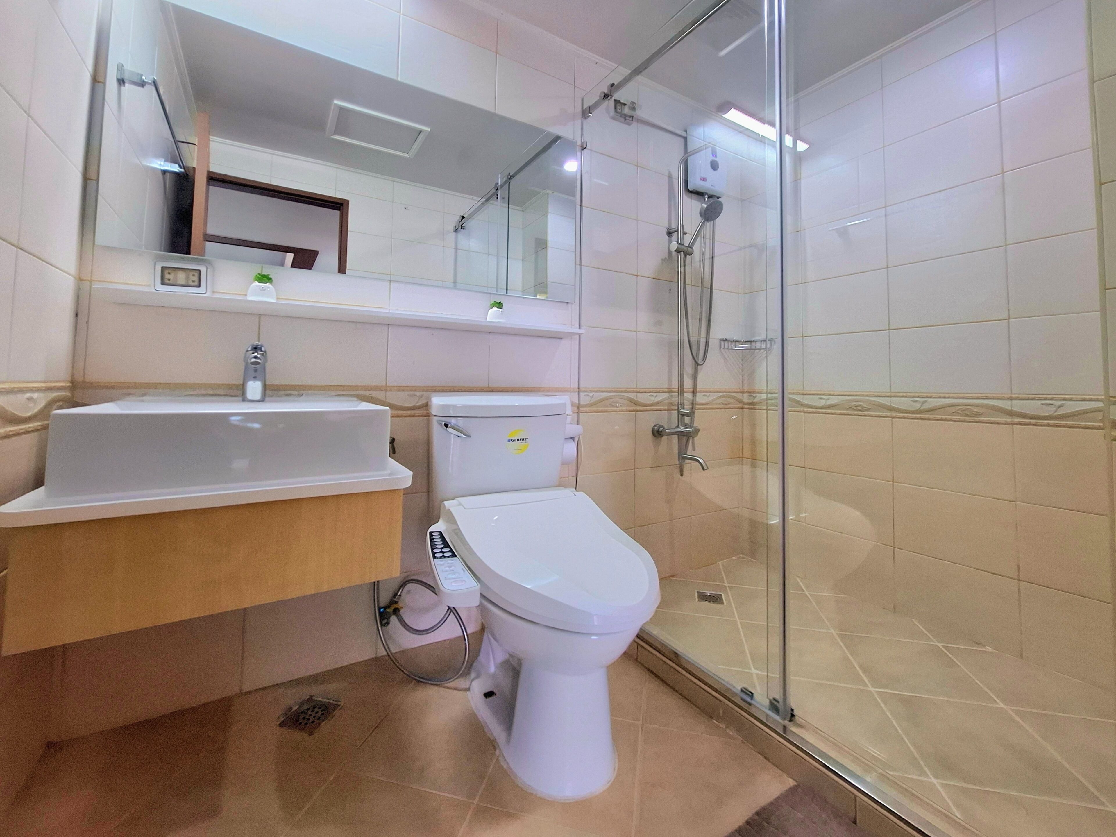 A modern bathroom with a glass-enclosed shower, a white sink, and a toilet.