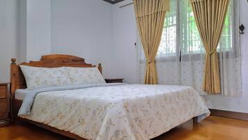A neatly made bed with floral bedding, a wooden headboard, and a nightstand beside it.