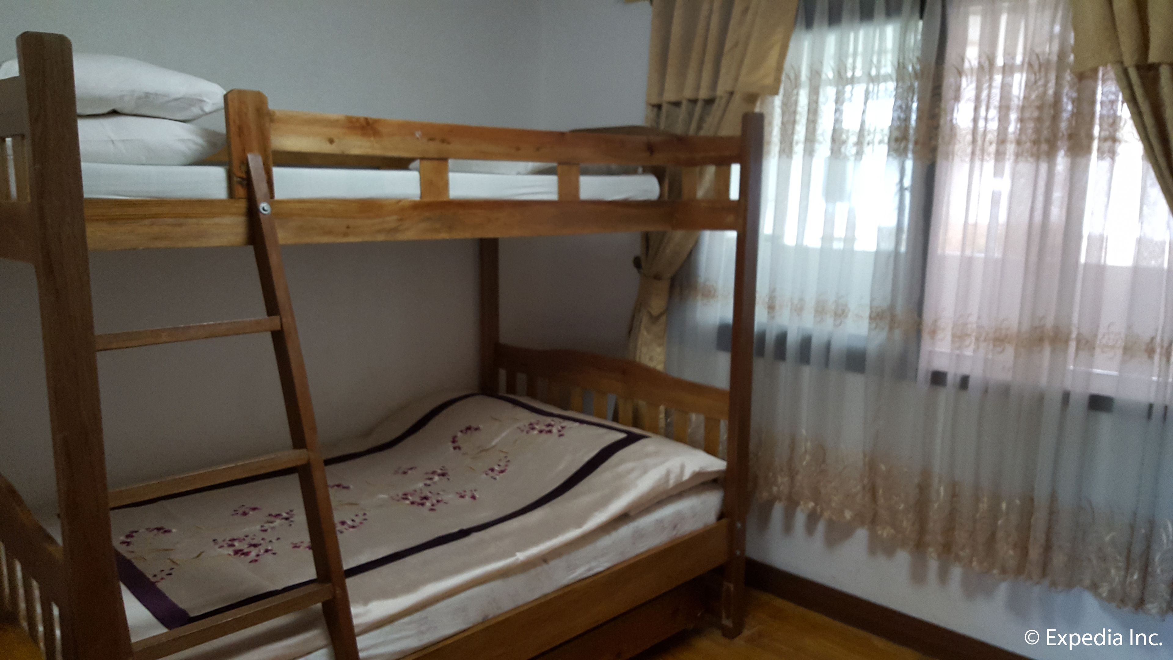 A bunk bed with a wooden frame and a lower bed with a floral bedspread.