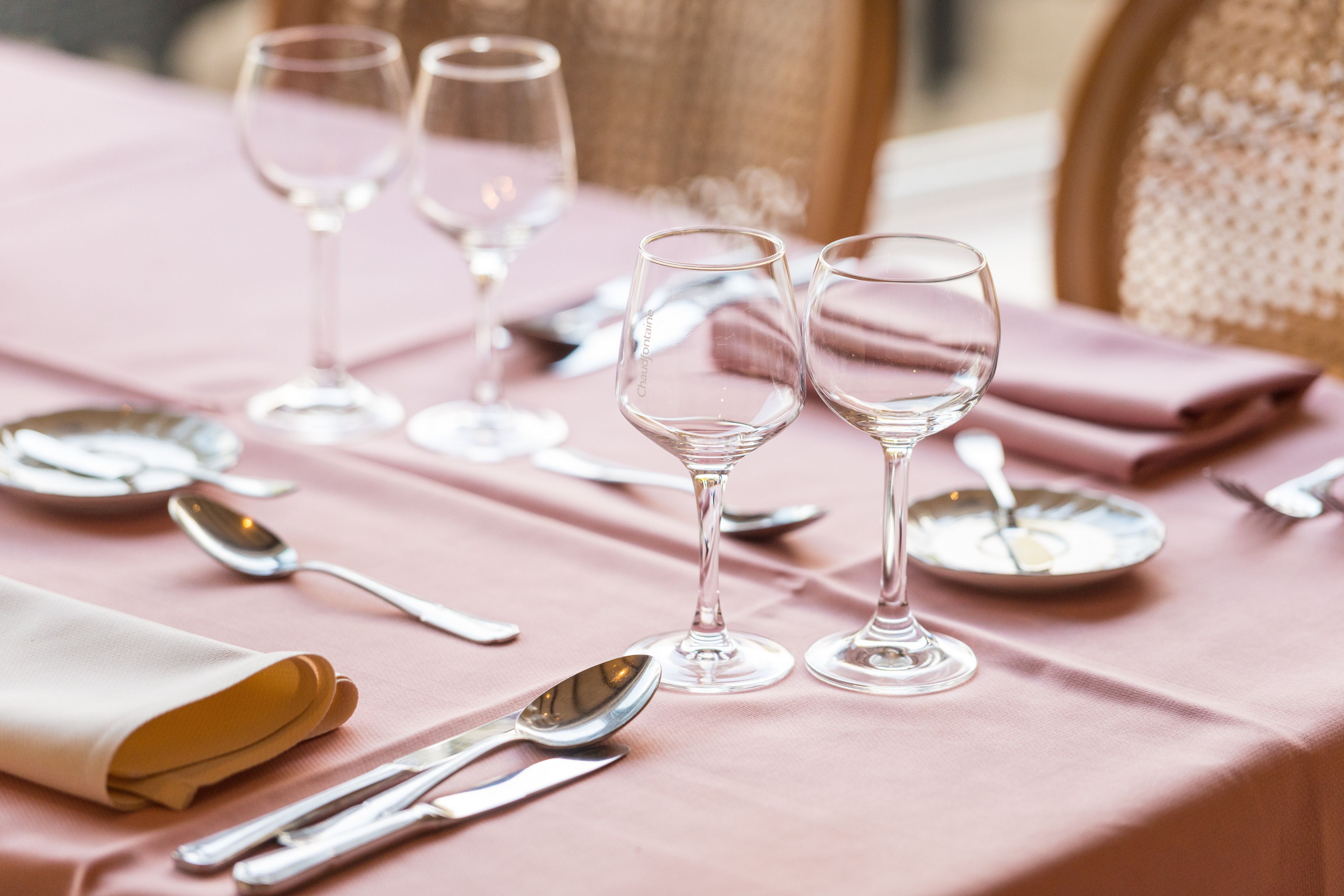 Una mesa servida con copas de vino, platos y cubiertos.