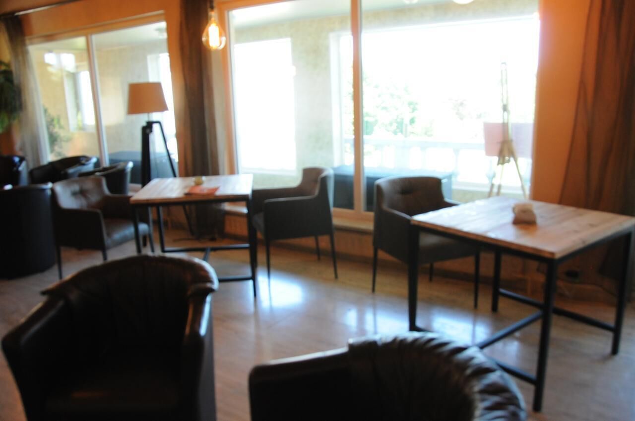 Quarto de hotel moderno com uma grande janela, uma mesa de madeira e assentos confortáveis.