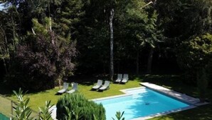 A swimming pool with lounge chairs and a well-maintained lawn.