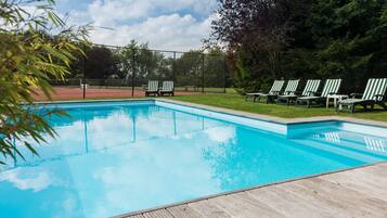 Een buitenzwembad, ligstoelen bij het zwembad