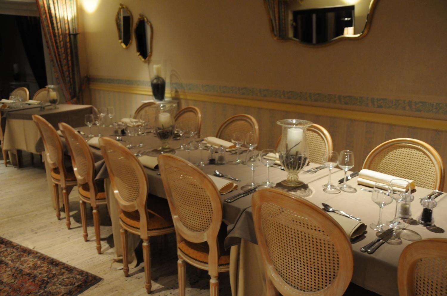 Ein formeller Speisesaal mit einem langen Tisch, der für eine Mahlzeit gedeckt ist, umgeben von hölzernen Stühlen.