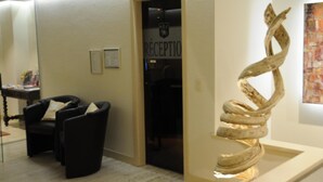 A reception area with a desk, chairs, and a large abstract sculpture.