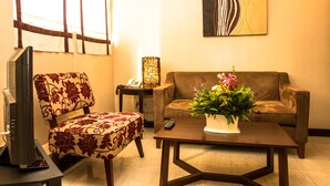 Una sala de estar con sofá, sillón, mesa de centro y televisor.