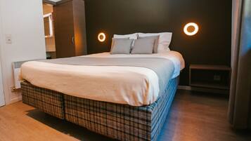 Une chambre à coucher moderne avec un grand lit, un mur de couleur sombre et deux appliques murales rondes.