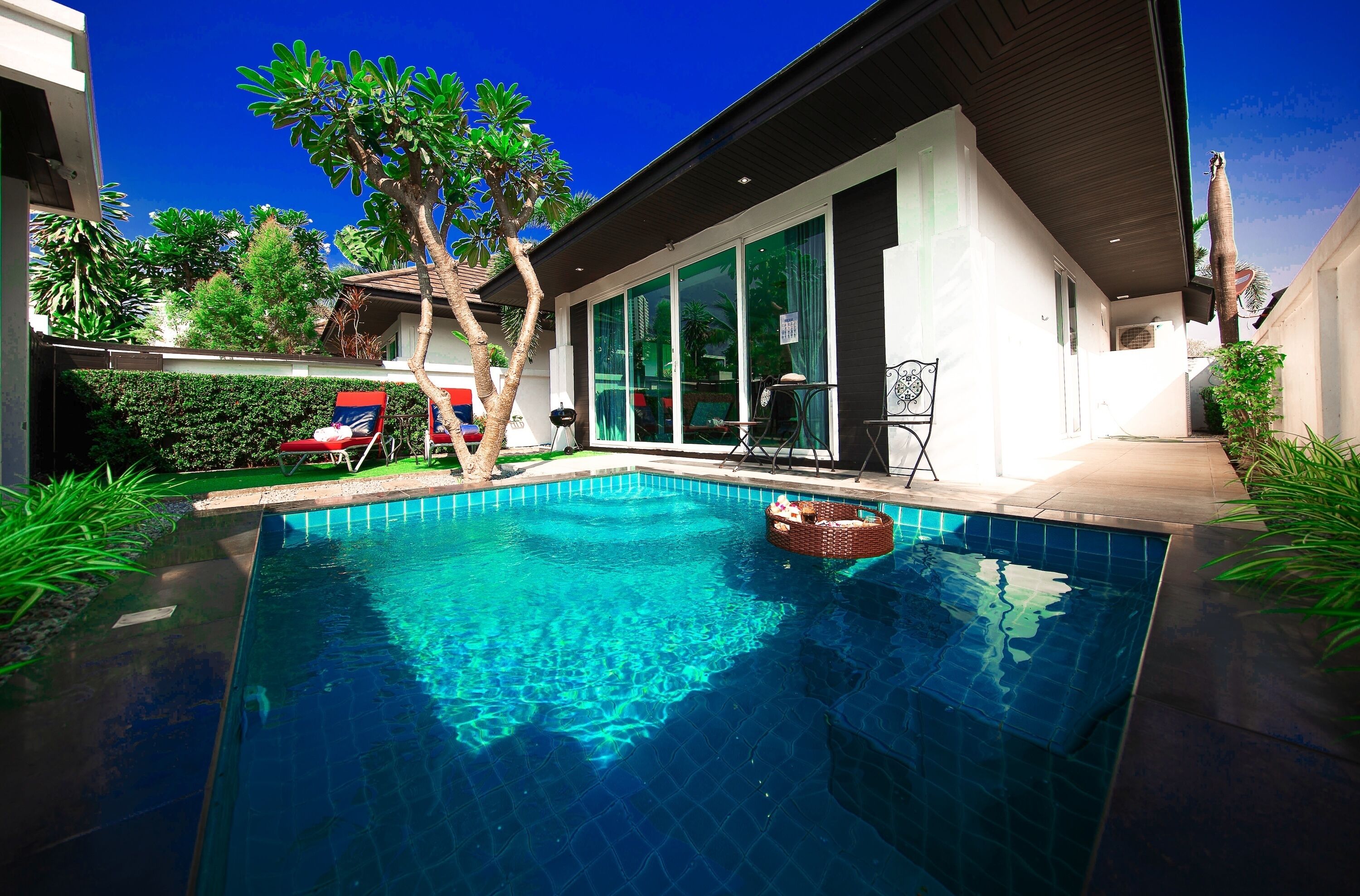 A modern house with a swimming pool, a covered patio, and a large window overlooking the pool.