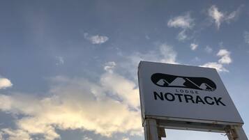 A sign for Lodge Notrack against a sky with clouds.