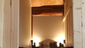 Une pièce chaleureuse, aménagée dans un chalet en bois, avec un lit, une table de chevet et une lampe.