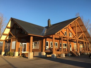A large wooden lodge with a prominent chimney, multiple windows, and a covered entrance area.