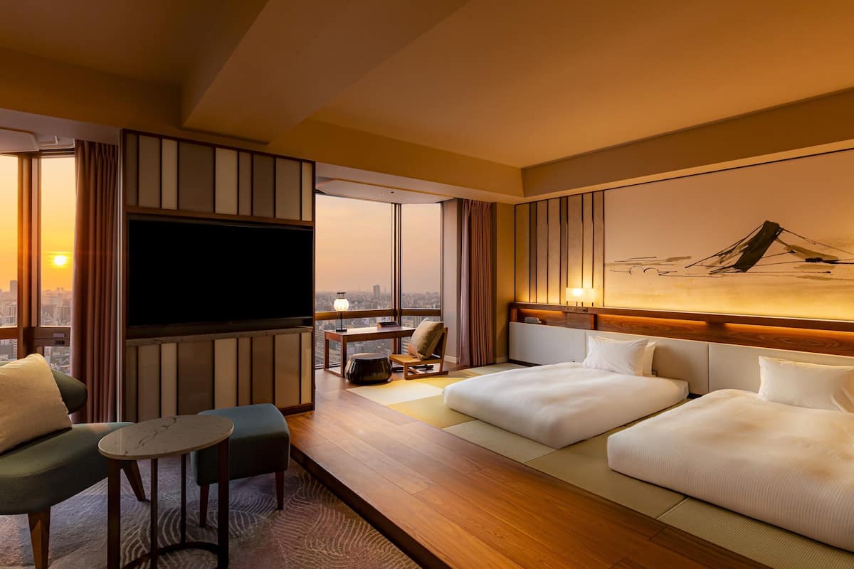 A hotel room with a large TV, a bed, a desk, and a chair.