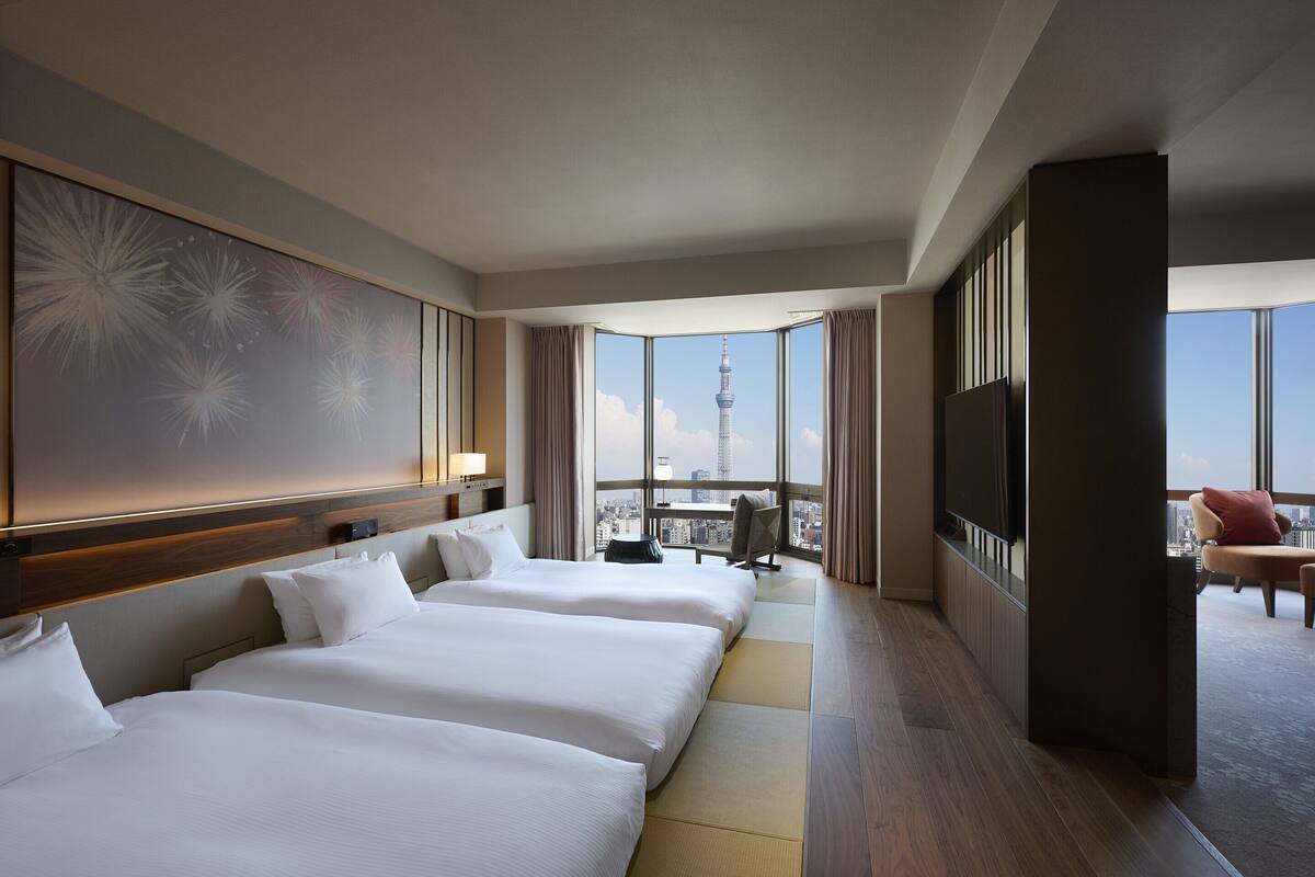 A hotel room with a large bed, a desk, and a view of a tower.