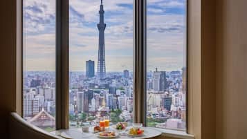 Uma área de refeições com uma mesa posta para o café da manhã, com vista para um horizonte urbano com uma torre imponente.