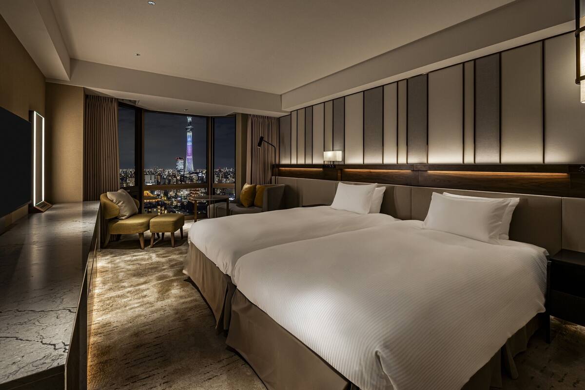 A hotel room with a large bed, a seating area with a view of the cityscape, and a modern design.