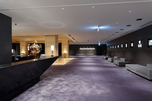 A modern lobby with a reception desk, seating area, and a large decorative piece.