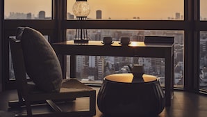 Una habitación moderna con vistas a la ciudad, una mesa con dos tazas, una lámpara y una silla.